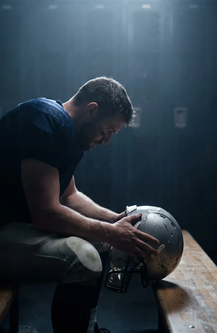 Athlete seated in a locker room holding his helmet
